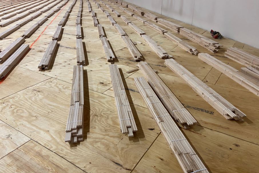 The plywood has been laid out in the gym and the wood flooring has been dispersed ready for installation