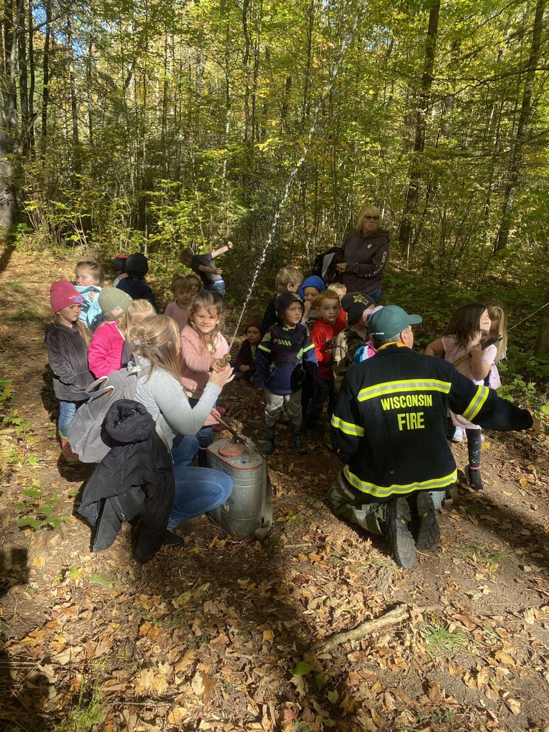 Students learning from a fire fighter and spraying water from tanks