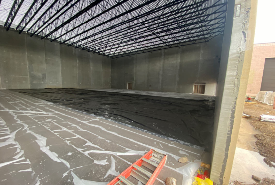The gym slab has been poured and covered with plastic for the curing process.
